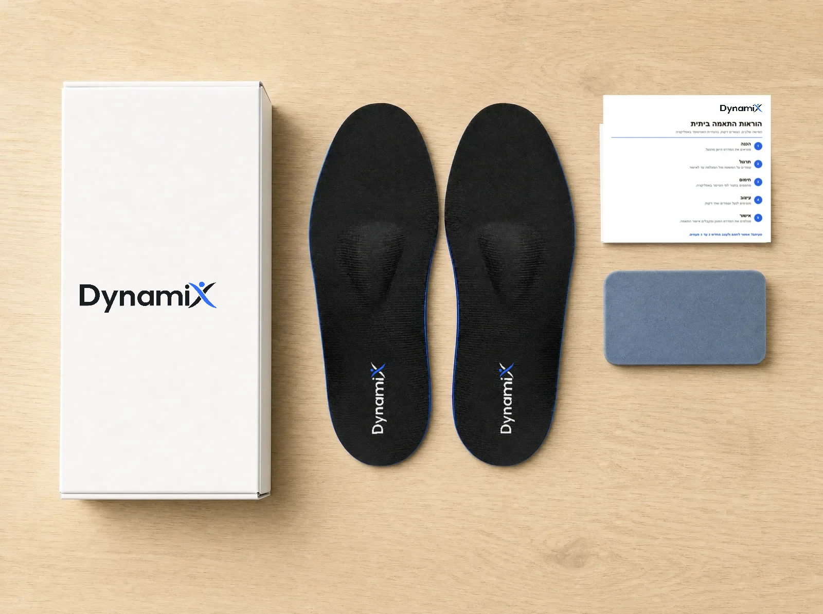 ערכת DynamiX על שולחן עץ: קופסה, זוג מדרסים, כרטיס הנחיות ומשטח תרגול